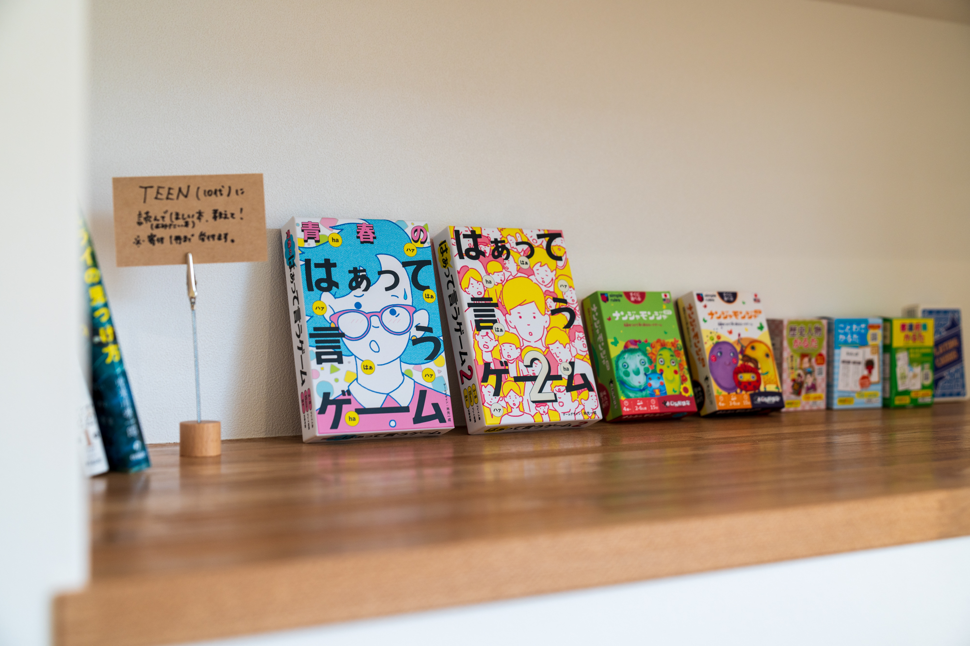ボードゲームやカードゲームを並べた木棚。10代向けの本の寄付を募る手書きのサインも置かれている