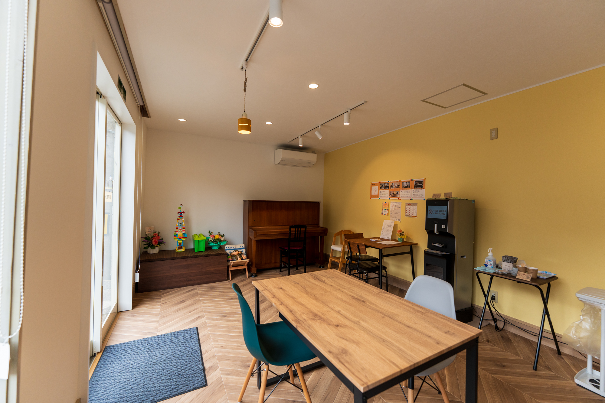 TEATROのチェックイン端末。画面とQRコードのほか、奥にピアノと木製テーブル、黄色い壁の掲示が見える