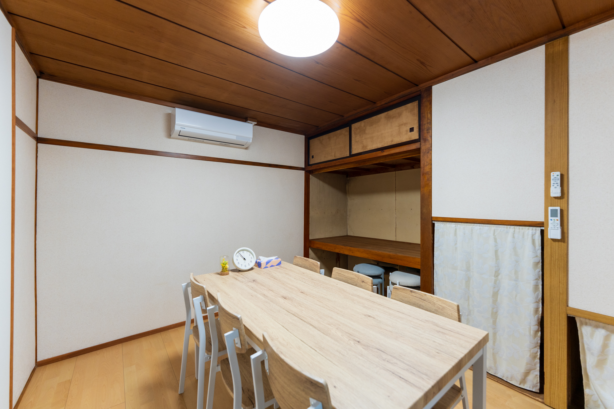 レンタル個室（約6畳）。淡色の長机と白脚の椅子6脚、木板天井と白壁、エアコン付きの和モダンな会議室